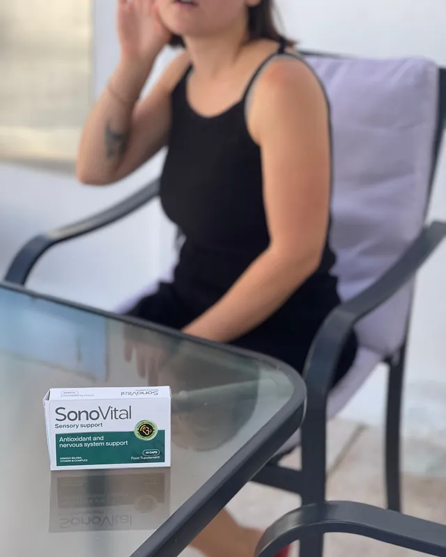 Donna seduta al tavolo che si tocca l'orecchio, confezione SonoVital sul tavolo