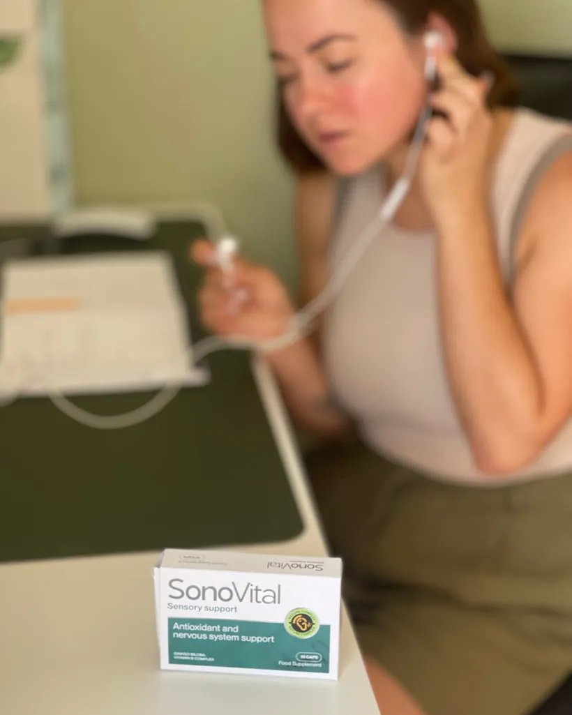 Donna con un auricolare al tavolo di lavoro, confezione SonoVital in primo piano